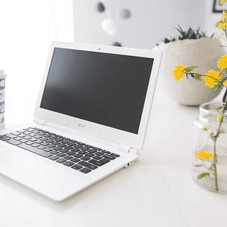 laptop sitting on a table with some flowers
